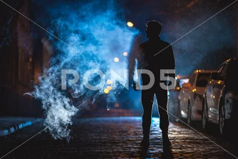 The man smoke on the street. Evening night time. Telephoto lens shot Stock Photos