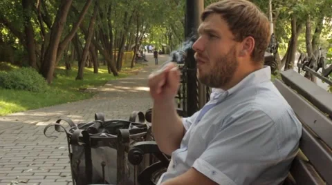 Man smokes on the bench in the park Stock Footage 68194075