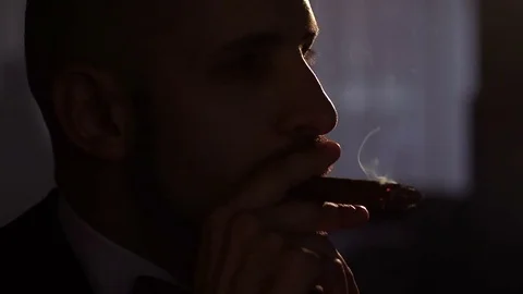 Man smokes a cigar in dark with artificial light. Stock Footage 82369826