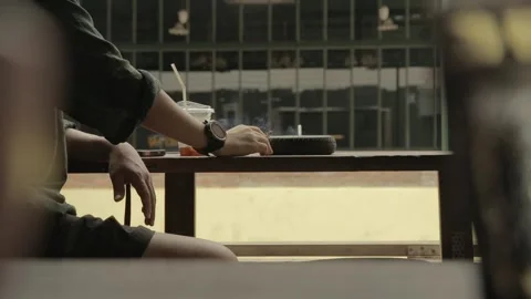 Man smokes cigarette drinks coffee use mobile phone on wooden table by street Stock Footage 278547651