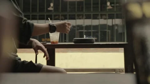 Man smokes cigarette drinks coffee use mobile phone on wooden table by street Stock-Footage 278547652
