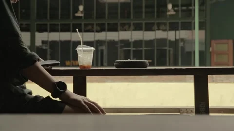 Man smokes cigarette drinks coffee use mobile phone on wooden table by street Stock-Footage 278547657
