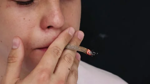 Man smokes a cigarette in slow motion on a black background 스톡 동영상 144698023