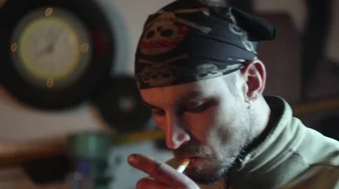 Man smokes a cigarette, tuning in to work in the garage. 库存影片 61485130