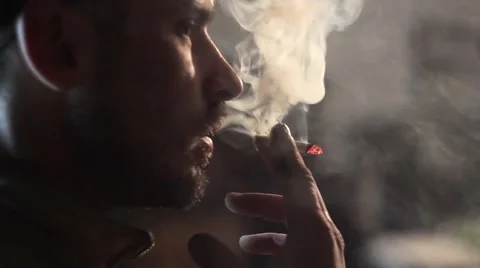 Man smokes a cigarette, tuning in to work in the garage. 库存影片 61485164
