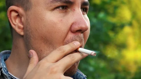 A man smokes a cigarette while outdoors in the woods Stock Footage 157712299