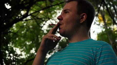 A man smokes a cigarette while standing on the street Stock Footage 157562170