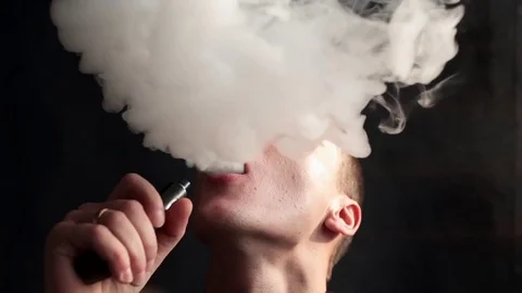 Man smokes electronic cigarette and and makes some smoke clouds, guy is vaping Video stock 71612890