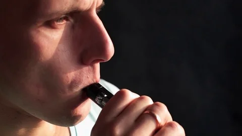 Man smokes electronic cigarette and lets off steam through the nostrils, guy is Stock Footage 71613153