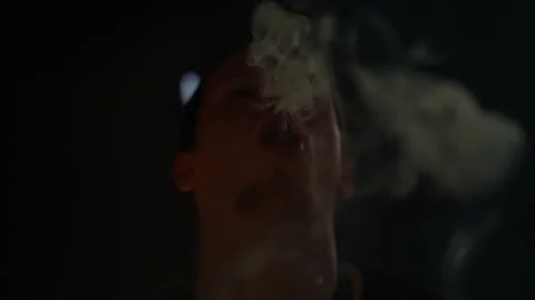 A man smokes a hookah and lets out a lot of smoke in a night club Stock Footage 239102562