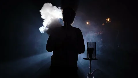 Man smokes hookah at bar in dark on background blue light. Night bar with hookah 库存影片 149126408