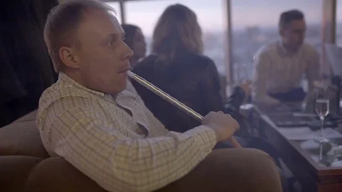 Man smokes a hookah in a restaurant close-up Stock Footage 76552528