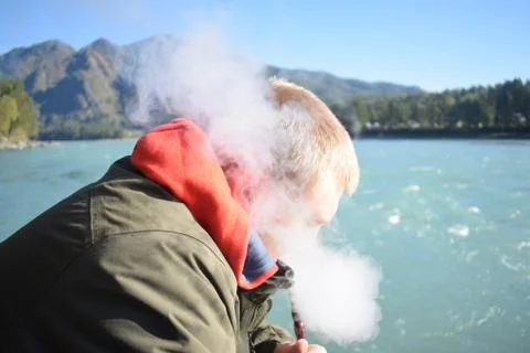 A man smokes a hookah by the river Stock Photos