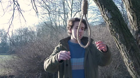Man smokes, thinks of hanging himself on rope. Trying to commit suicide in park Stock Footage 149324674