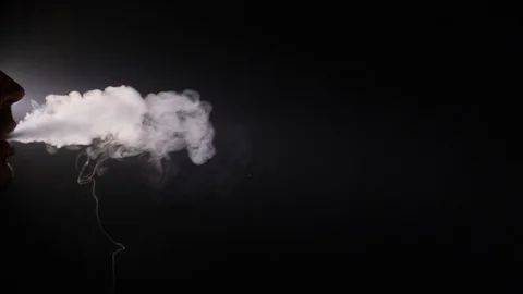 A man smokes a vape on a black background close-up. Slow motion Stock Footage 128056381