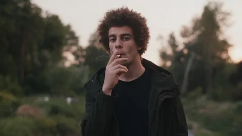 Man Smoking Cigarette and Looking At Camera Stock Footage 258357464