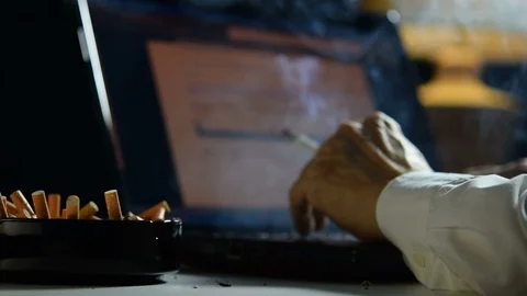 Man smoking cigarette and working on a laptop computer . Video stock 125543315