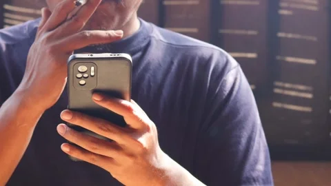 Man smoking cigarette while using smartphone Видео 334049247