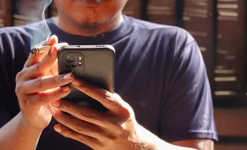Man smoking cigarette while using smartphone Stock Photos