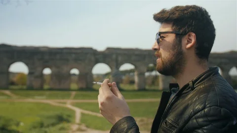 Man is smoking a cigarette while waiting in the park. Stock Footage 106620374