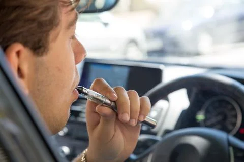 Man smoking an e-cigarette as he drives a car Stock Photos