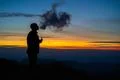 The man smoking an electronic cigarette on the sunset background Photo