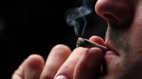 Man smoking a joint, close up on black Stock Footage