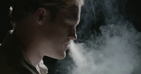 Man smoking older cigarette with trailing smoke and dramatic lighting. Stock Footage 209621401