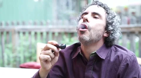 Man smoking pot marijuana from pipe and coughing Stock Footage 52371714