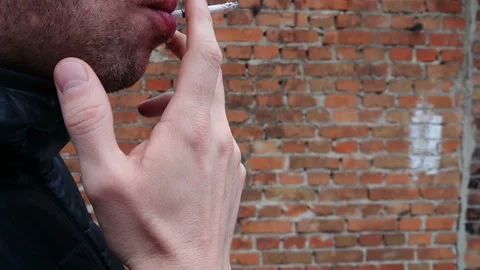 Man is smoking on red brick wall closeup, slow motion Stock Footage 101396519