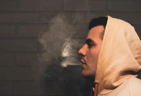 Man is smoking Vape Pod System at home near the gray wall. Electronic cigar.. Stock Photos
