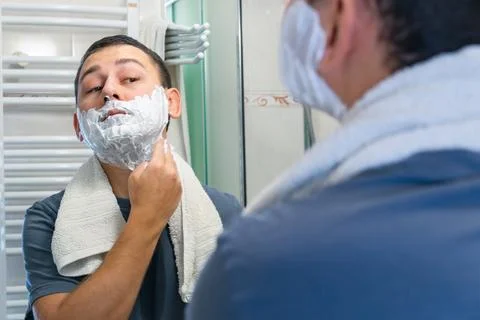 Man smoothing shaving cream while viewing reflection in mirror Stock Photos