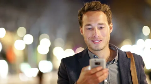 Man sms texting using app on smart phone at night Stock Footage