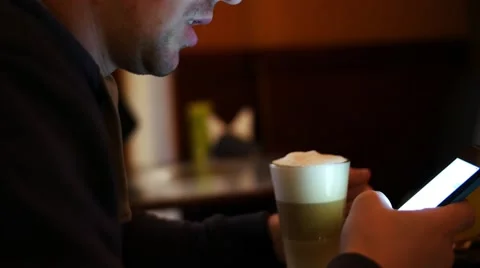 Man sms texting using app on smart phone at cafe drinking coffee. Handsome young 스톡 동영상 60641863