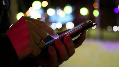 Man sms texting using app on smartphone at night in city, winter time. closeup Vidéo 70069731