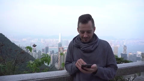 Man sms texting using app on smart phone in city. Handsome young man using Stock Footage 72124890