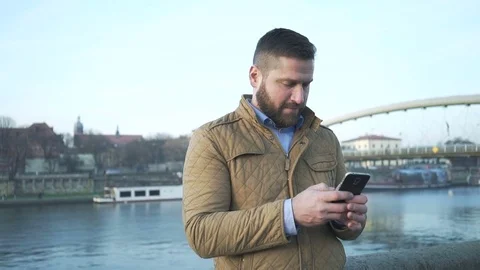 Man sms texting using app on smartphone, on background of the river, steadycam Vídeo Stock 72775769