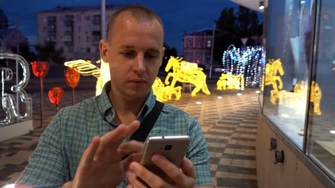 Man sms texting using app on smart phone at night in city. Handsome young Stock Footage 76637343