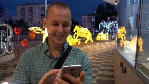Man sms texting using app on smart phone at night in city. Handsome young Stock-Footage 76637601