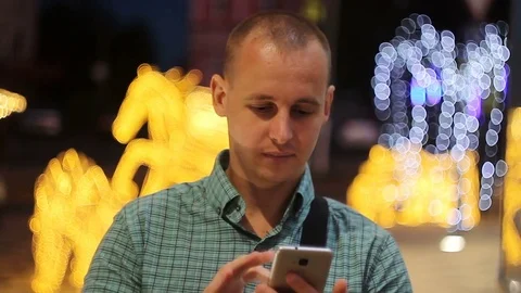 Man sms texting using app on smart phone at night in city. Handsome young Stock-Footage 76638690