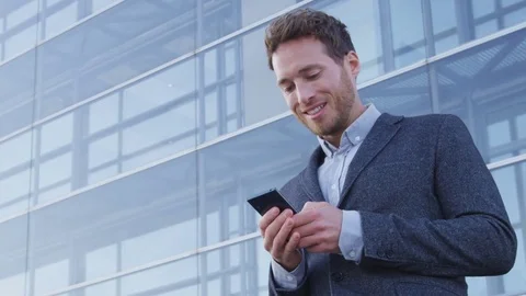 Man sms texting using app on smart phone in city business district Stock Footage 79898298