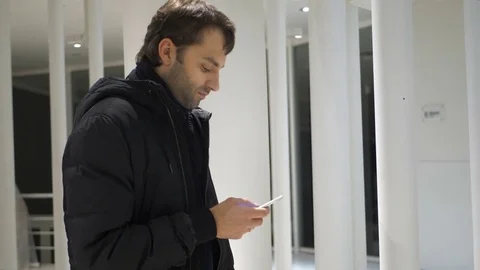 Man sms texting using app on smart phone at night in city. Handsome young Stock Footage 82336512