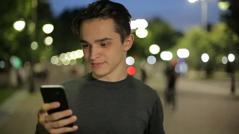 Man sms texting using app on smart phone at night in city.  Stock Footage 90759466