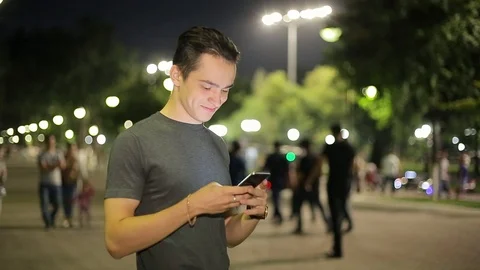 Man sms texting using app on smart phone at night in city.  Stock Footage 90772270