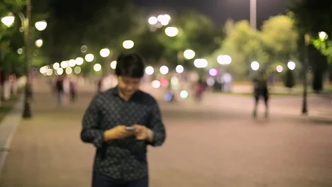 Man sms texting using app on smart phone at night in city. Stock Footage 90776687