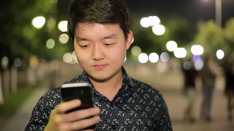 Man sms texting using app on smart phone at night in city. Stock Footage 90778053
