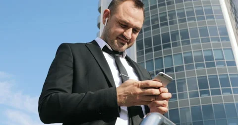 Man sms texting using app on smart phone in city business district. Young Stock Footage 92410012