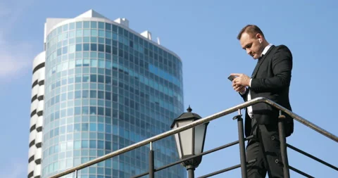 Man sms texting using app on smart phone in city. Handsome young businessman Stock Footage 92411317