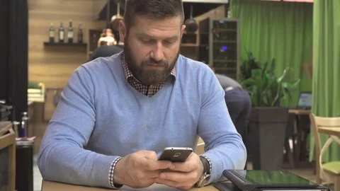 Man sms typing using app on smartphone, in pub, cafe, indoor, steadicam shot 库存影片 73067628