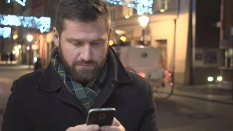 Man sms typing using on smartphone app, night, city, Christmas, close steadycam 库存影片 72781794